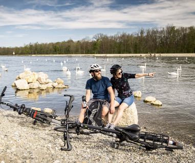 Radtour entlang der Donau in Elchingen Zwei Radfahrer, die mit ihren Rädern in Elchingen an der Donau Rast machen und die Schwäne beobachten.